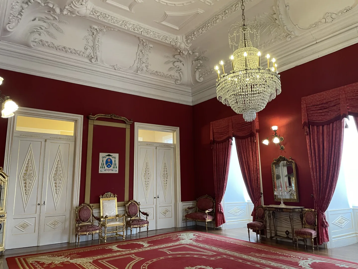 Salle du Trône du Palais Épiscopal de Porto avec murs rouges, mobilier d'apparat et lustre en cristal