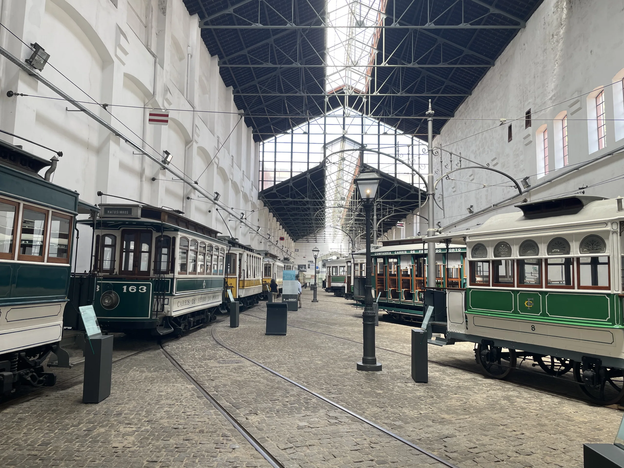 Intérieur du Museu do Carro Eléctrico de Porto avec alignement de tramways anciens sur voie ferrée en pavés