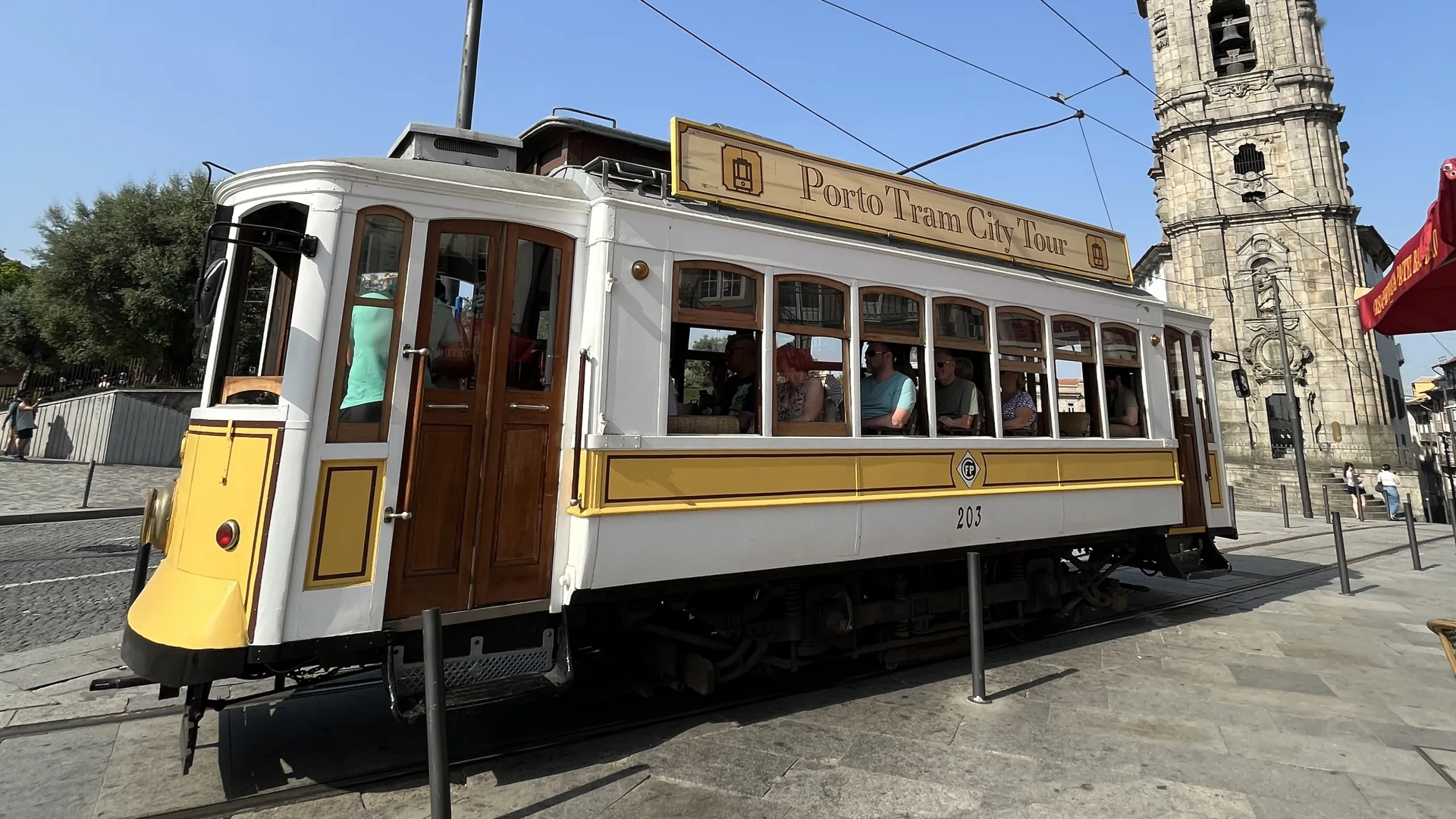 Tramway historique nº203 à Porto passant devant la Torre dos Clérigos avec des passagers à bord